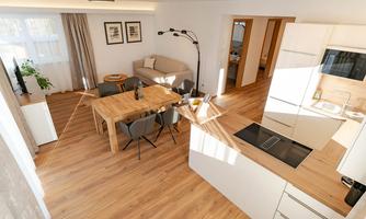 A modern apartment with an open living and dining area. The bright decor includes a dining table, a comfortable couch, and a well-equipped kitchen.