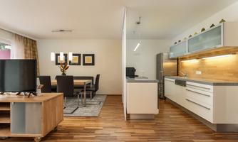 A modernly furnished living kitchen with wooden flooring. The room is bright and offers a dining table as well as a fully equipped kitchen.