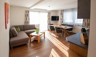 A modern apartment with a cozy living area and a dining space. Large windows provide plenty of daylight and a welcoming atmosphere.