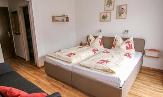 A cozy bedroom with two single beds and comfortable duvets. Next to the bed is a sofa and decorative pictures on the wall.