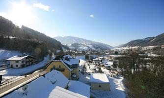 A wintry mountain village with snow-covered roofs and a clear blue sky. The surrounding mountains are majestic and radiate tranquility.