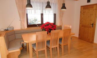 An inviting dining area with a wooden table and eight chairs. Decorated with red flowers and a cozy seating area.
