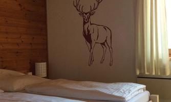 A cozy bedroom with two beds and wooden paneling. On the wall is a picture of a deer.
