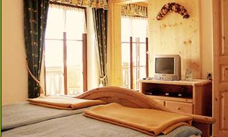 A cozy bedroom with two beds and wood paneling. Large windows let in plenty of light and offer a view outside.