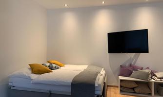 A modern bedroom with a double bed and various pillows. A television is located on the wall.