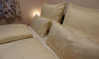 A cozy bed with several yellow pillows and blankets. Soft light creates a relaxed atmosphere.