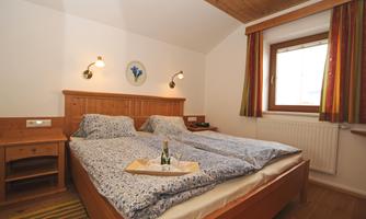 A cozy bedroom with a double bed and fresh bedding. On the nightstand is a tray with champagne and glasses.