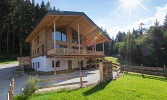 A modern wooden house in a green environment. The sun is shining and surrounds the building with natural light.