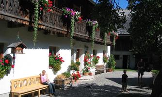 A picturesque courtyard with blooming plants and a cozy bench. Children are playing on the paved path under radiant sunshine.