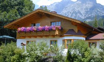 A charming wooden house with a flower box full of colorful flowers. In the background, majestic mountains can be seen.