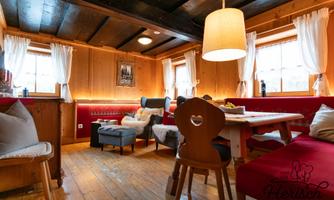A cozy room with wooden walls and red upholstery. There is a large table and comfortable seating, inviting a relaxing atmosphere.