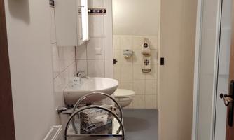 A modern bathroom with a sink, a mirror, and a shower. Towels are hanging on the wall, and a towel rack is in the room.