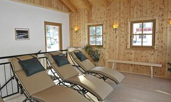 A cozy room with wood paneling and large windows. Three loungers invite you to relax.