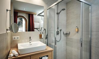 A modern bathroom with a glass shower and a wooden sink. The room is bright and cheerfully designed.