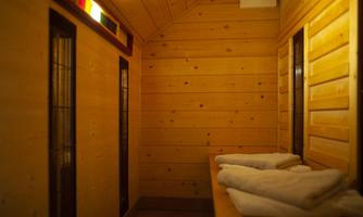 A quiet sauna room with wooden paneling and folded towels on a bench. Soft lighting creates a relaxing atmosphere.