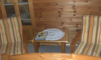 A cozy room with two chairs and a small table. On the table, there is a tablecloth and a book.