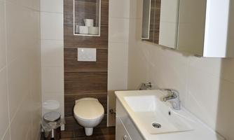 A modern bathroom with bright tiles. It features a sink, a toilet, and a large mirror.