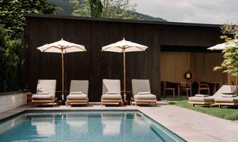 A pool area with loungers and sun umbrellas and an outdoor lounge.