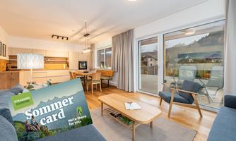 A modern living room with a bright and inviting atmosphere. In the foreground is a summer brochure offering vacation options.