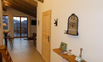 A modern hallway with wooden ceilings and a warm atmosphere. Decorative items and a mirror are on the wall table.