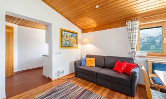 A cozy living room with a gray sofa and colorful cushions. A magnificent mountain view can be seen through the window.