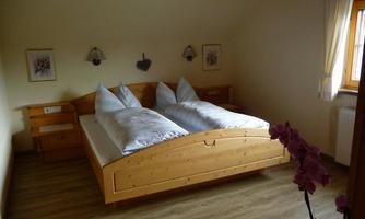 A cozy bedroom with a large bed and two pillows. The warm wood tones create an inviting atmosphere.