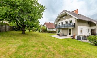 A modern house with a large garden and an adjoining balcony. The surroundings are green and peaceful, perfect for relaxing.