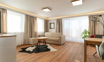 A modern living room with a beige sofa, a table, and a cowhide rug. Large windows provide plenty of natural light and a pleasant atmosphere.