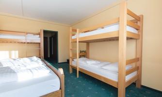 A simple bedroom with two bunk beds and a single bed. The walls are yellow and the floor is green.