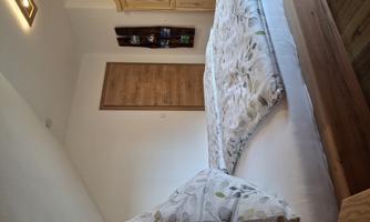 A cozy bedroom with a large bed and decorative pillows. There is a wooden door and a wooden wardrobe on the wall.