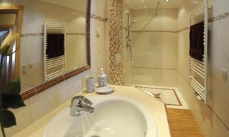 A modern bathroom with a sink and a shower. The walls are bright and there are decorative elements.