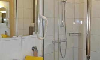 A modern bathroom with a shower and a sink. Yellow towels are neatly laid out.