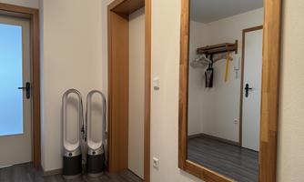 A modern hallway with two fan heaters and a large mirror. In the background, two doors are visible that lead to additional rooms.