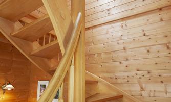 A bright wooden staircase leads up into a cozy interior. The walls are made of light wood, creating a warm atmosphere.