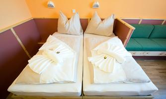 A cozy room with two beds, decorated with clean white towels. The walls are painted in warm colors, creating an inviting atmosphere.