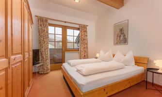 A cozy bedroom with a double bed and two pillows. Large windows provide plenty of light and a beautiful view.