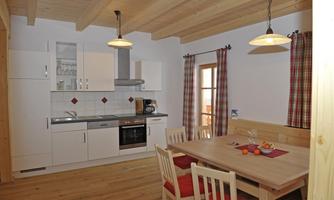A bright kitchen with a wooden ceiling and a large dining table. The room is friendly and invites you to eat.