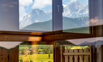 A cozy room with windows that showcase a beautiful mountain landscape and a green valley. The view is clear and picturesque, with many details of nature.