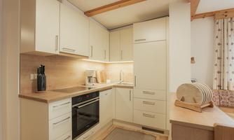 A modern kitchen with bright cabinets and a wooden countertop. There is an oven, a sink, and some kitchen utensils visible.