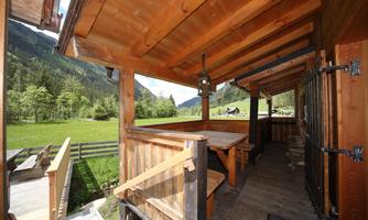 A rustic wooden porch overlooking green meadows and mountains. The space offers an inviting atmosphere for relaxed hours outdoors.