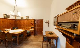 A cozy dining area made of wood with a large table and chairs. A vintage radio is on the wall, and the decor adds a rustic charm.