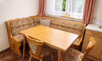 A cozy dining area with a wooden tray and upholstered benches. The windows let in plenty of daylight and create an inviting atmosphere.