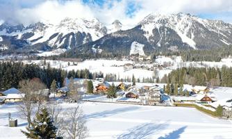 A picturesque winter landscape with snow-covered mountains and a small village. The scenes are peaceful and inviting under a clear blue sky.