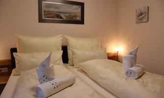 A cozy bedroom with a double bed and decorative towels. Soft lighting and elegant bed linen create an inviting atmosphere.