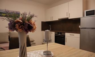 A cozy kitchen with modern furniture and a dining table. On the table is a vase with colorful flowers.
