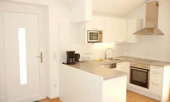 A modern kitchen with white cabinets and a cooking island. The amenities include a stove, an oven, and a microwave.