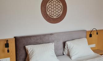 A cozy bedroom with a large bed and white pillows. Above the headboard hangs a decorative wall art.