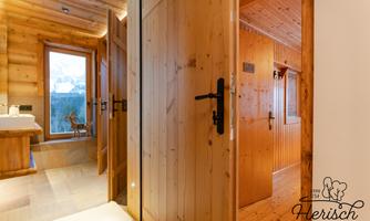 A cozy wooden hallway with doors to various rooms. The space features natural materials and a warm atmosphere.