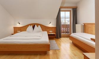 A cozy bedroom with wooden beds and a large window. The decor is simple and modern with a warm, inviting ambiance.