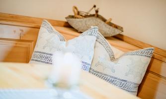 Cozy cushions with blue patterns on a wooden bench. In the background, a small decorative ship can be seen.
